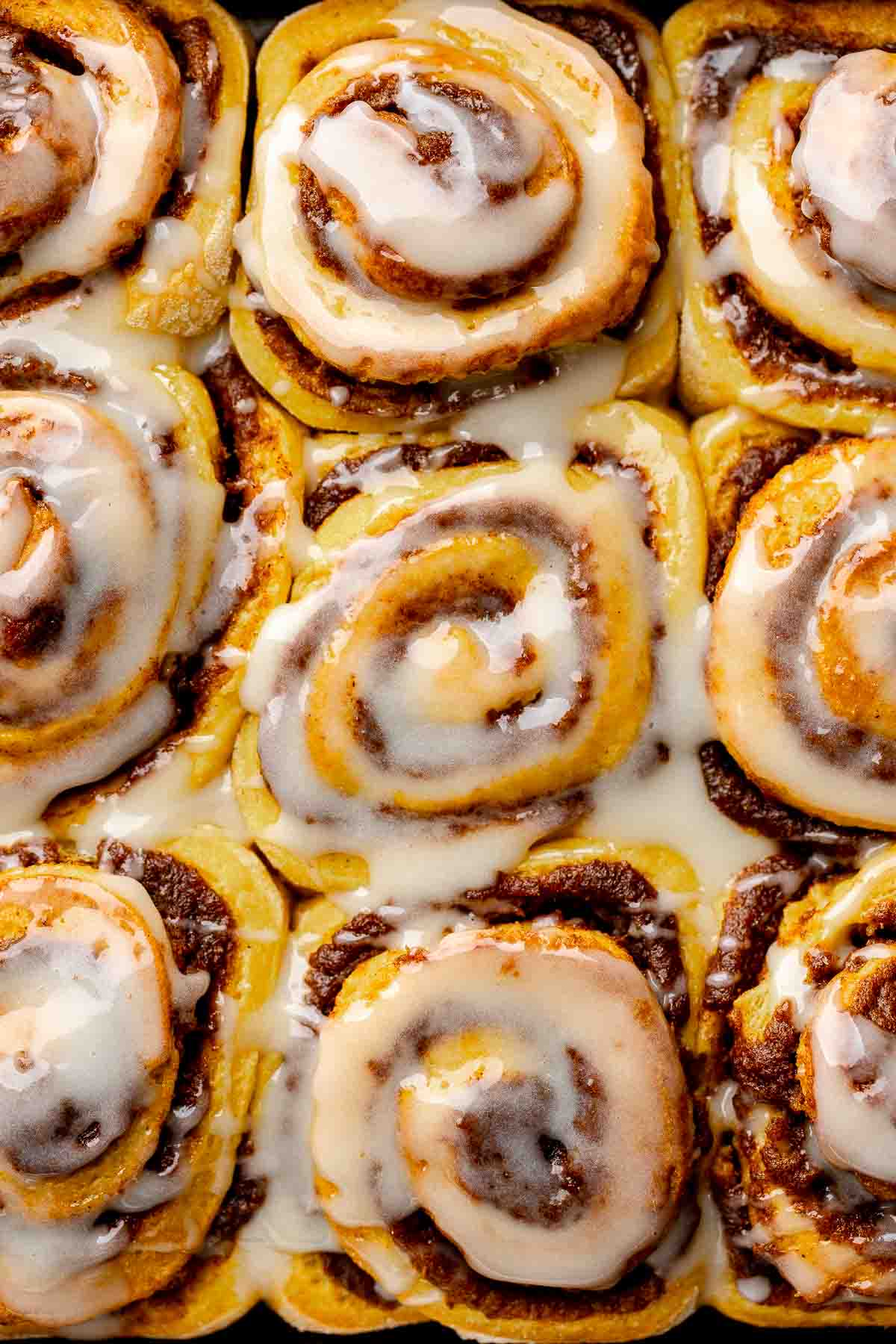Close-up of gooey gluten free pumpkin cinnamon rolls with icing drizzled over the tops of the swirled rolls.