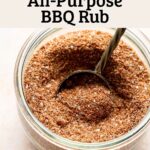 Homemade bbq seasoning blend in glass jar with gold measuring spoon.