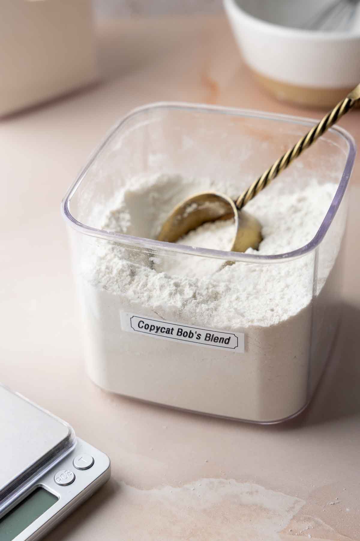 Container labeled &ldquo;Copycat Bob&rsquo;s Blend&rdquo; filled with gluten-free flour mixture and scoop.