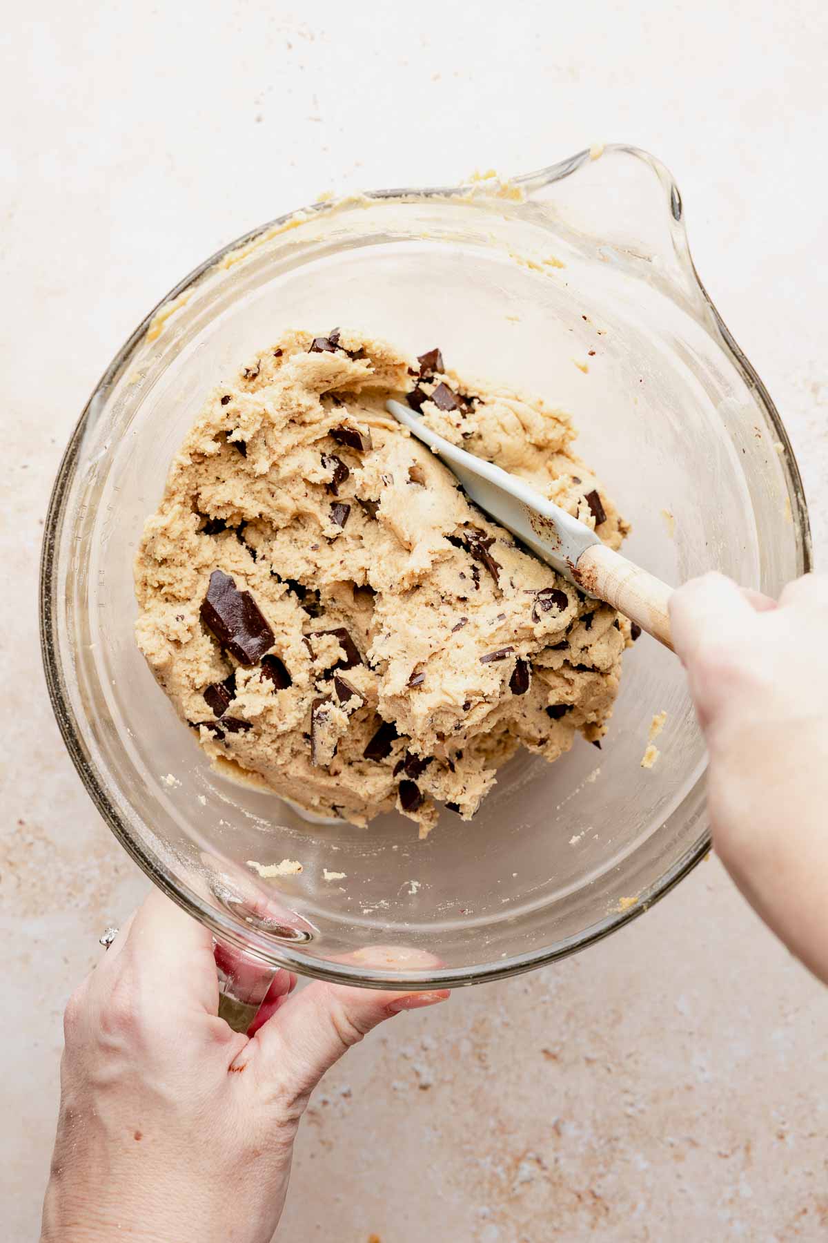 Chopped chocolate added to peanut butter cookie dough in a mixing bowl.