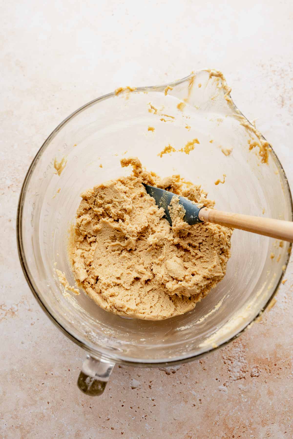 Peanut butter cookie dough mixed in a glass bowl with a spatula.