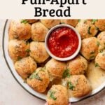 Plate of gluten-free cheesy garlic pull-apart bread with marinara dipping sauce in center.