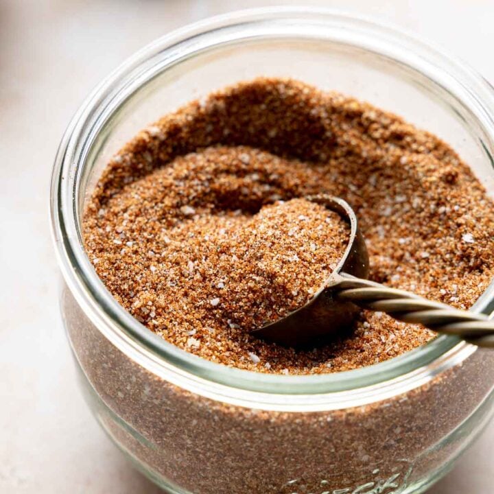 Homemade bbq seasoning blend in glass jar with gold measuring spoon.