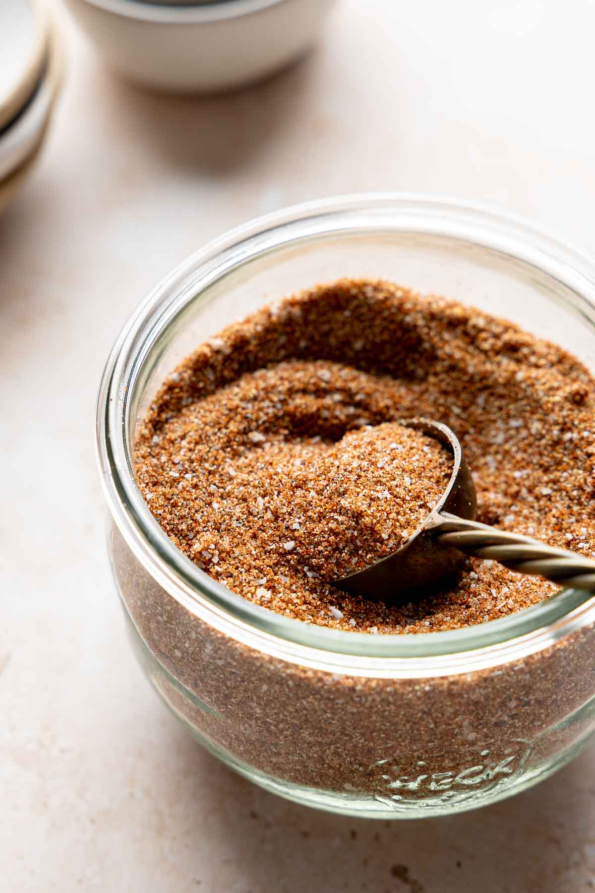 Homemade bbq seasoning blend in weck jar with gold measuring spoon.
