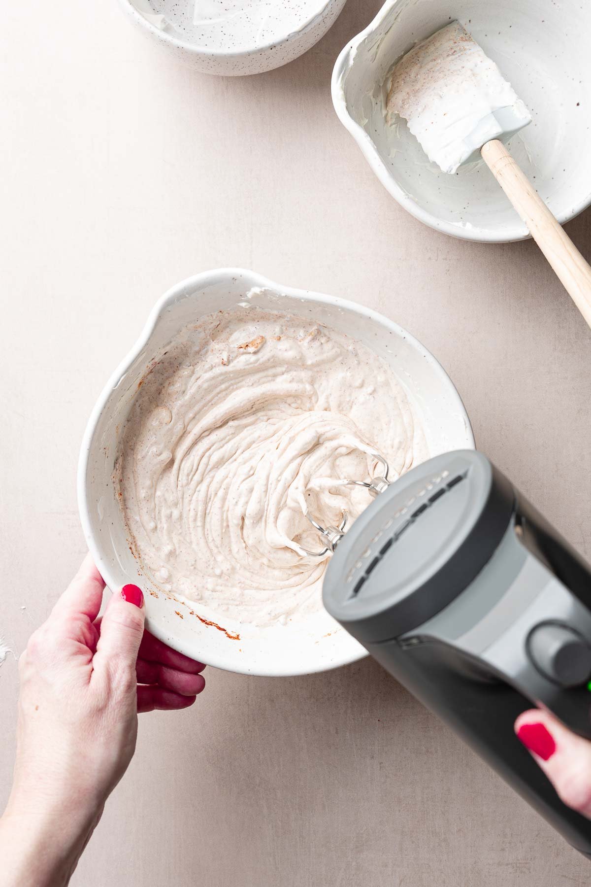 Cream cheese taco dip base in bowl blended with hand mixer.