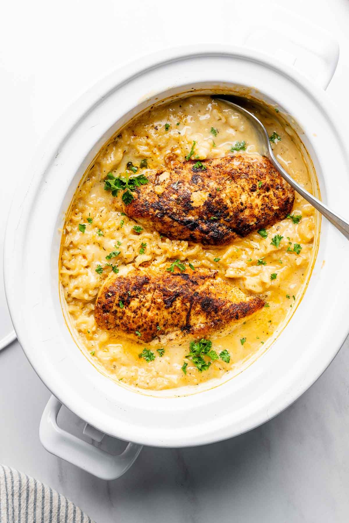 Overhead view of creamy chicken and rice casserole in a white crock pot.