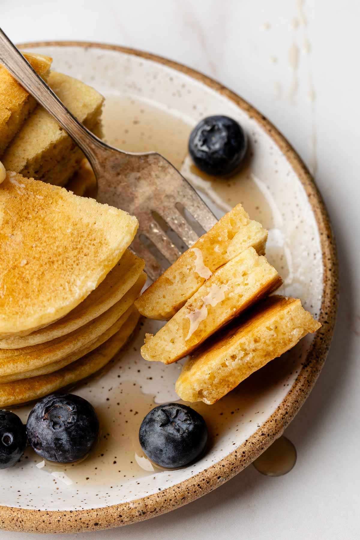 Gluten-free pancake bites on a fork, drizzled with syrup.