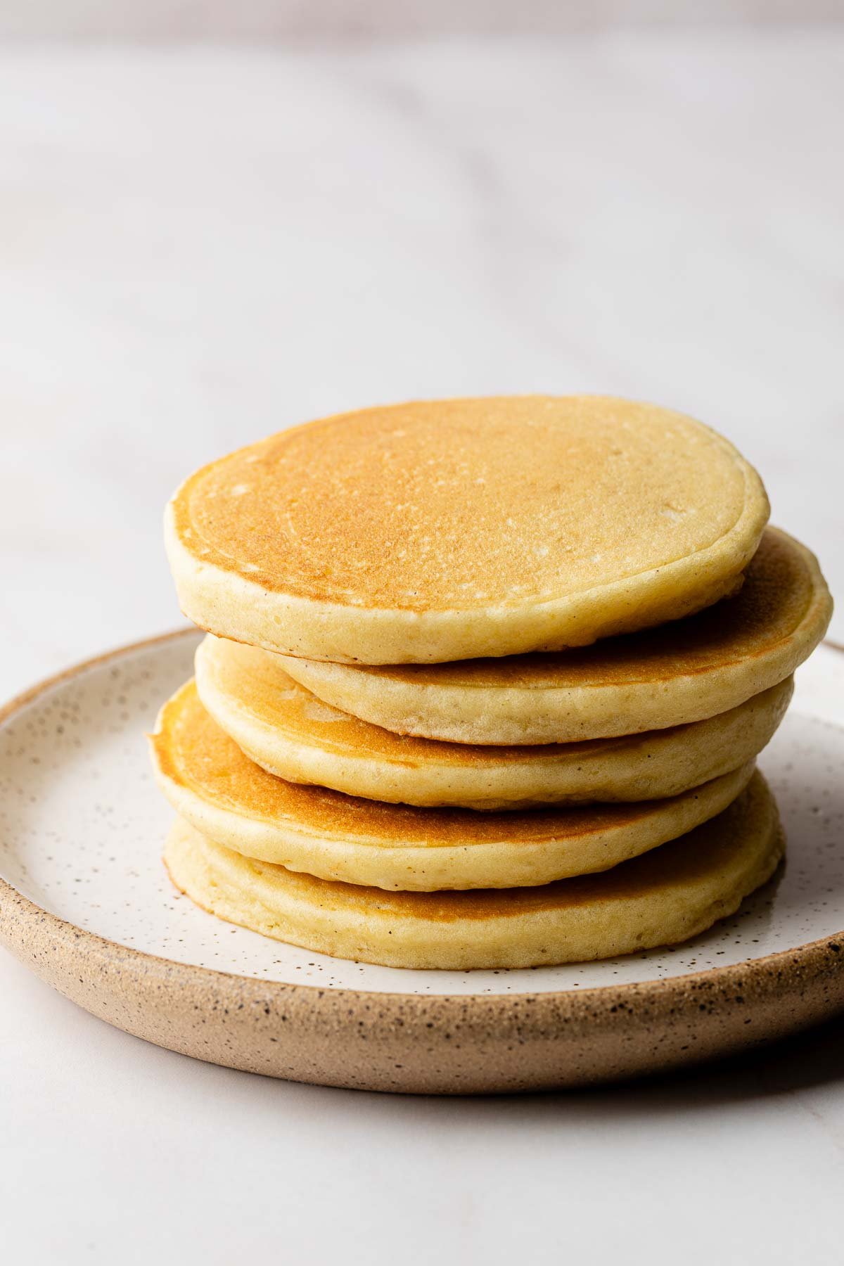 A stack of cooked gluten free pancakes on a plate.