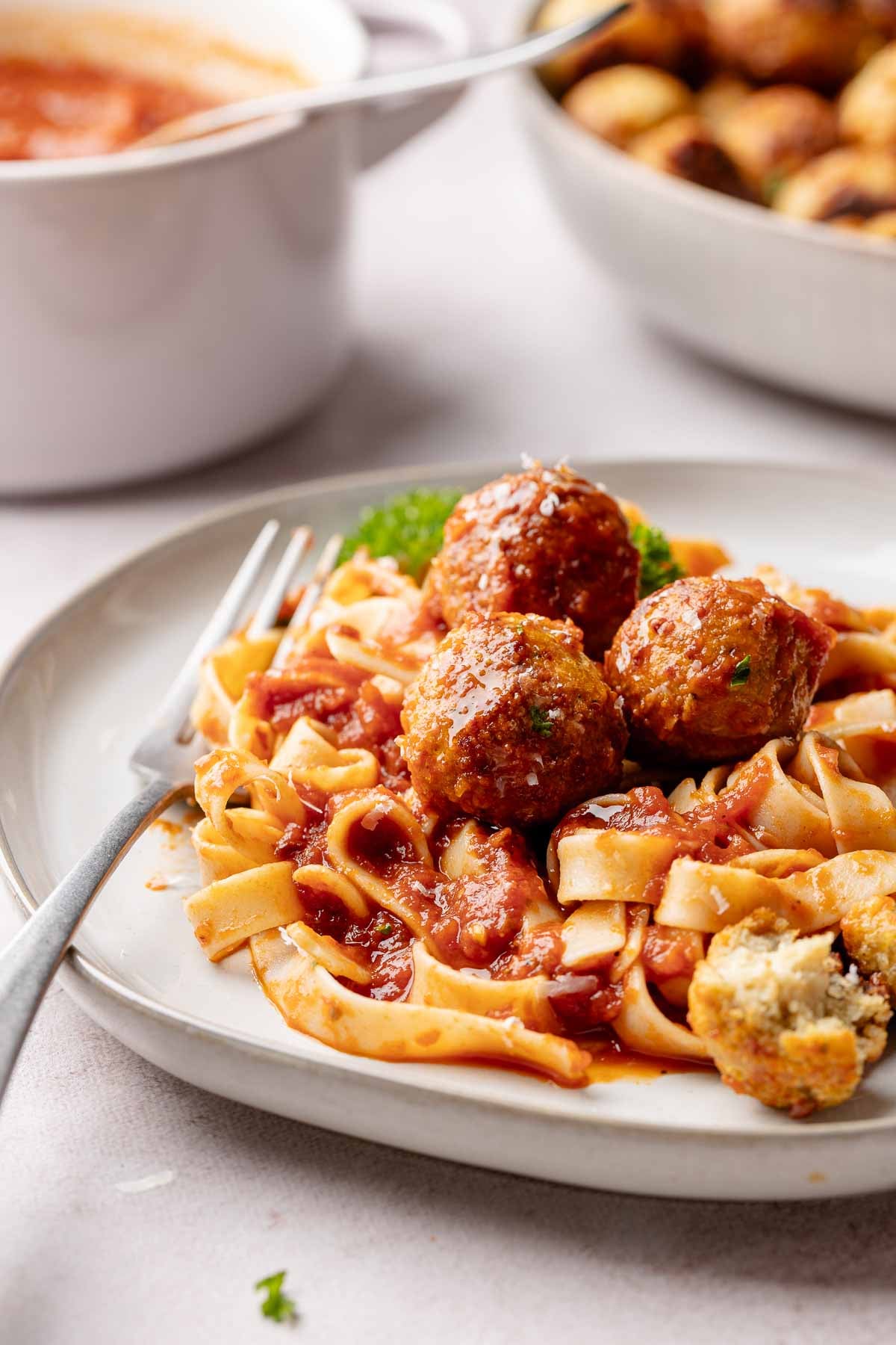A plate of spaghetti and meatballs garnished with parsley.