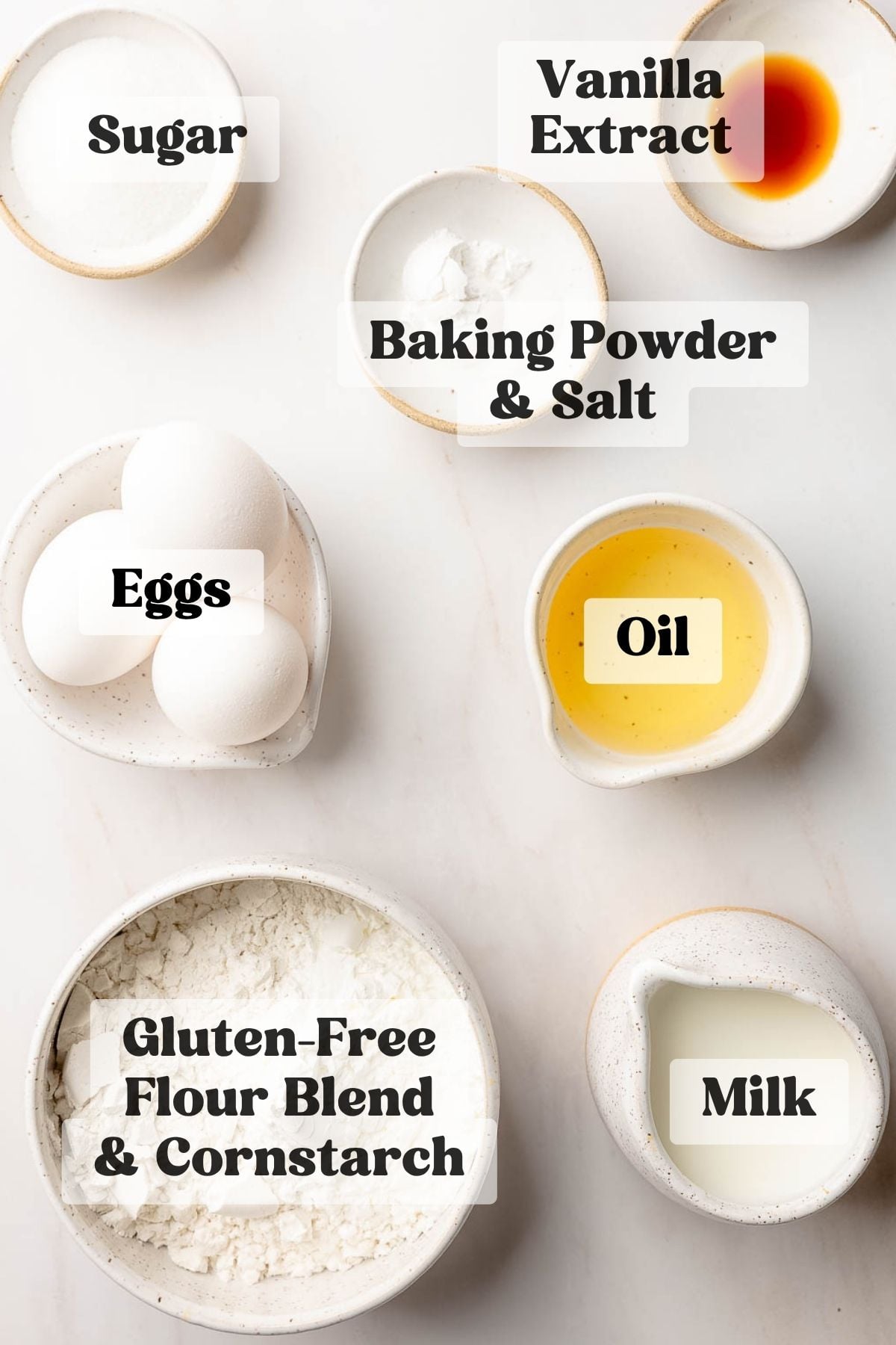 Ingredients for gluten free waffles measured out in bowls on white marble surface.