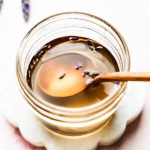Close-up overhead shot of golden lavender syrup in a jar with a spoon.