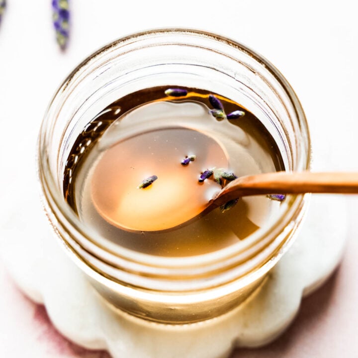 Close-up overhead shot of golden lavender syrup in a jar with a spoon.