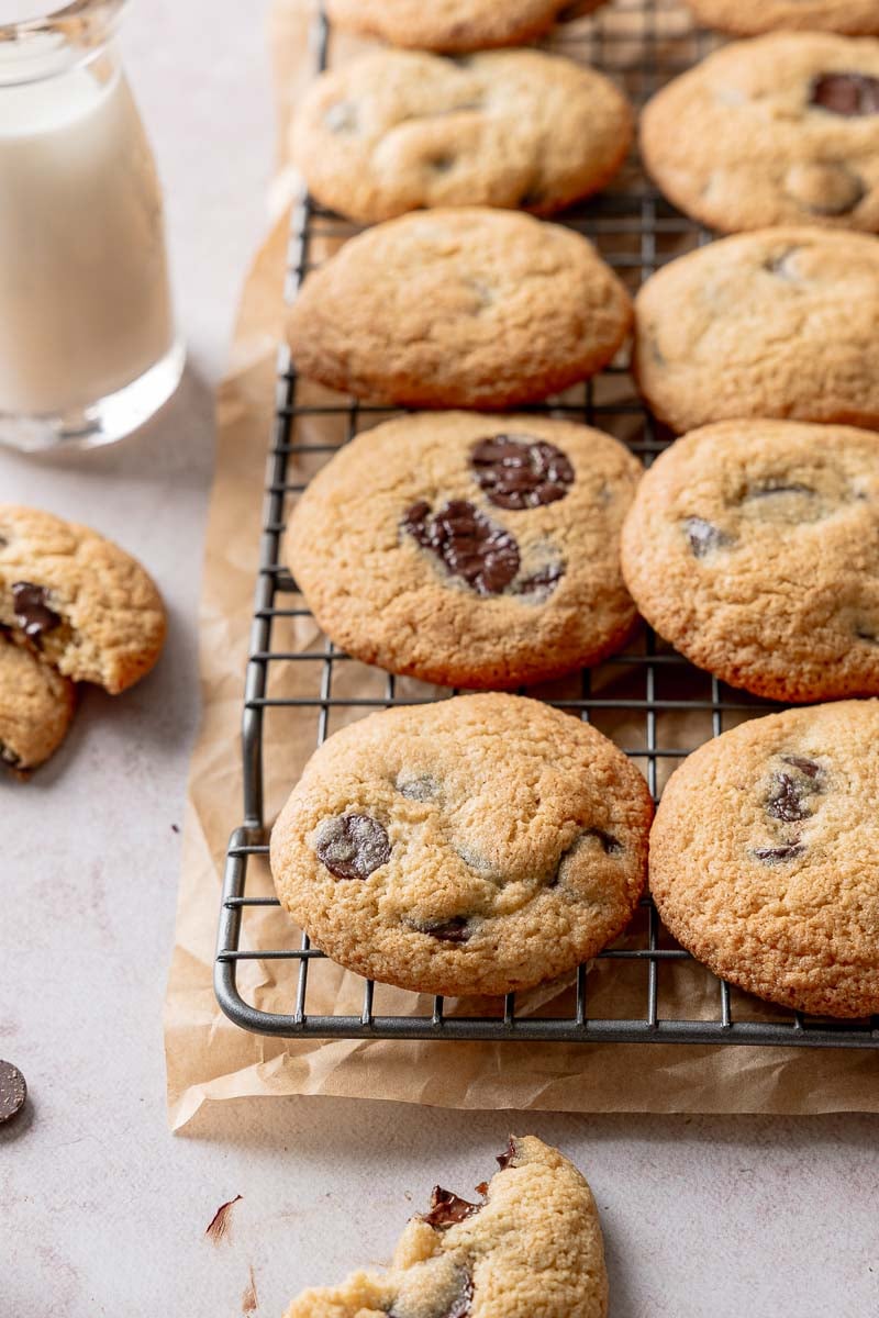 Almond flour chocolate chip cookies on wire rack next to glass bottle of milk.