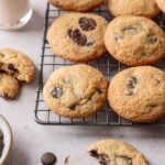 Almond flour chocolate chip cookies on wire rack next to glass bottle of milk.