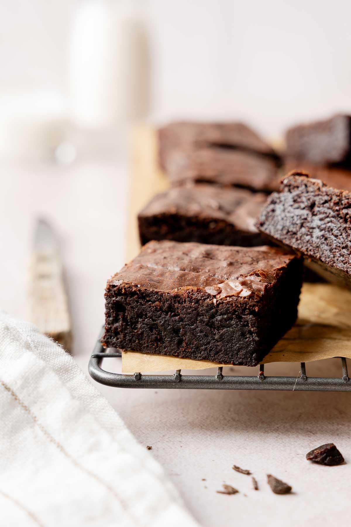 Brownies stacked on wire rack, showing fudgy interior and crinkled tops.