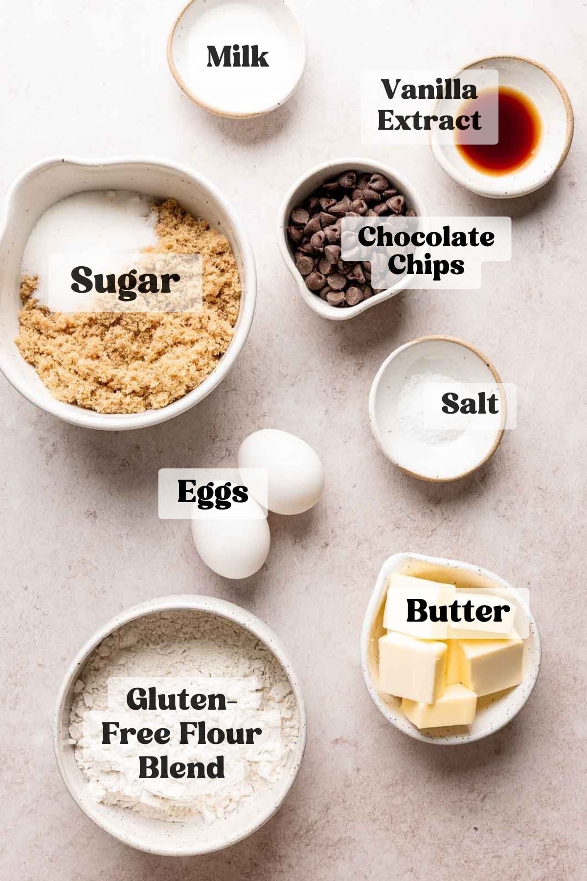 Ingredients for gluten free brown butter blondies (sugar, chocolate chips, gluten-free flour, eggs, and butter) measured out in bowls.