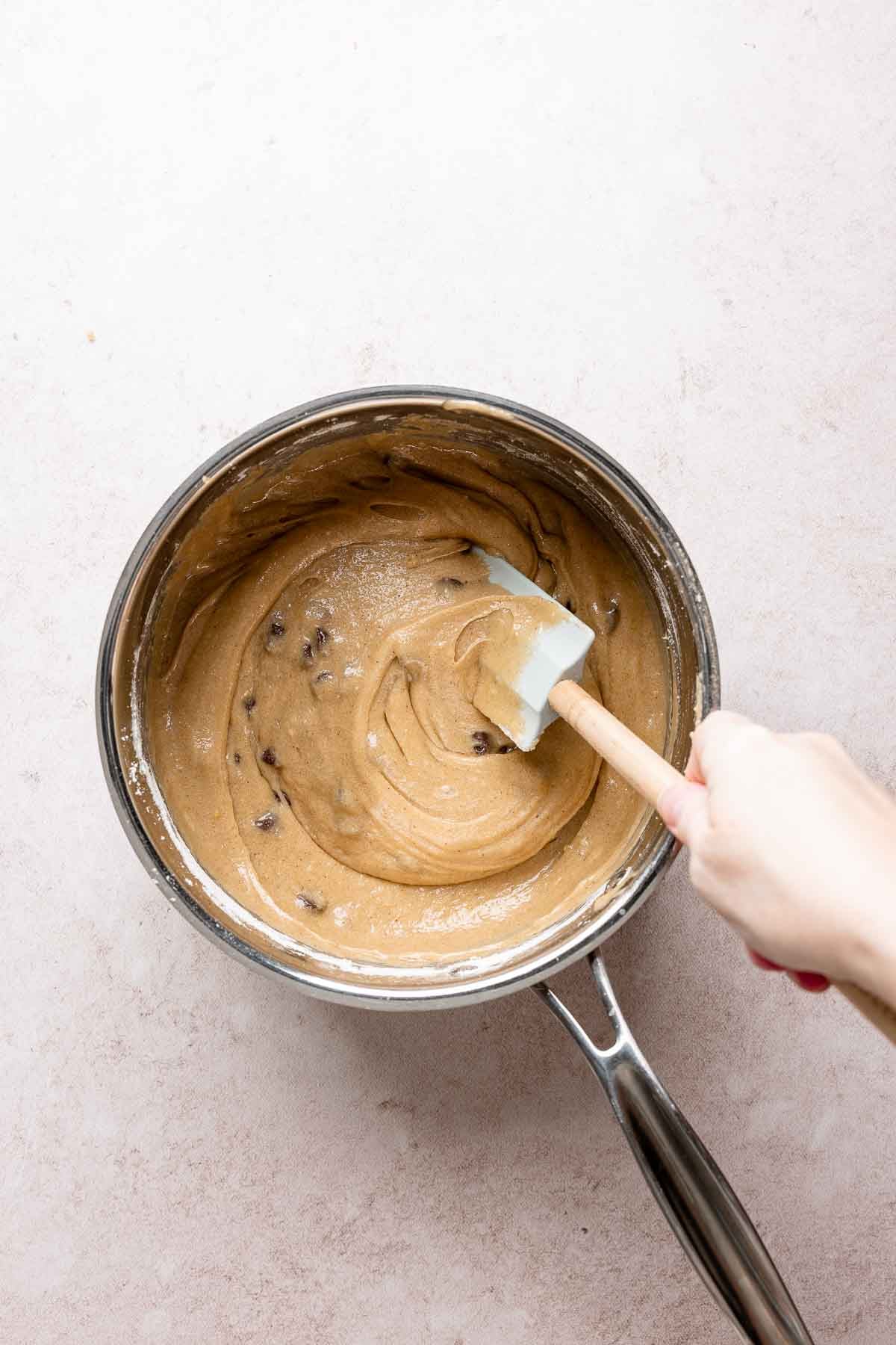 Chocolate chips folded into blondie batter with spatula.