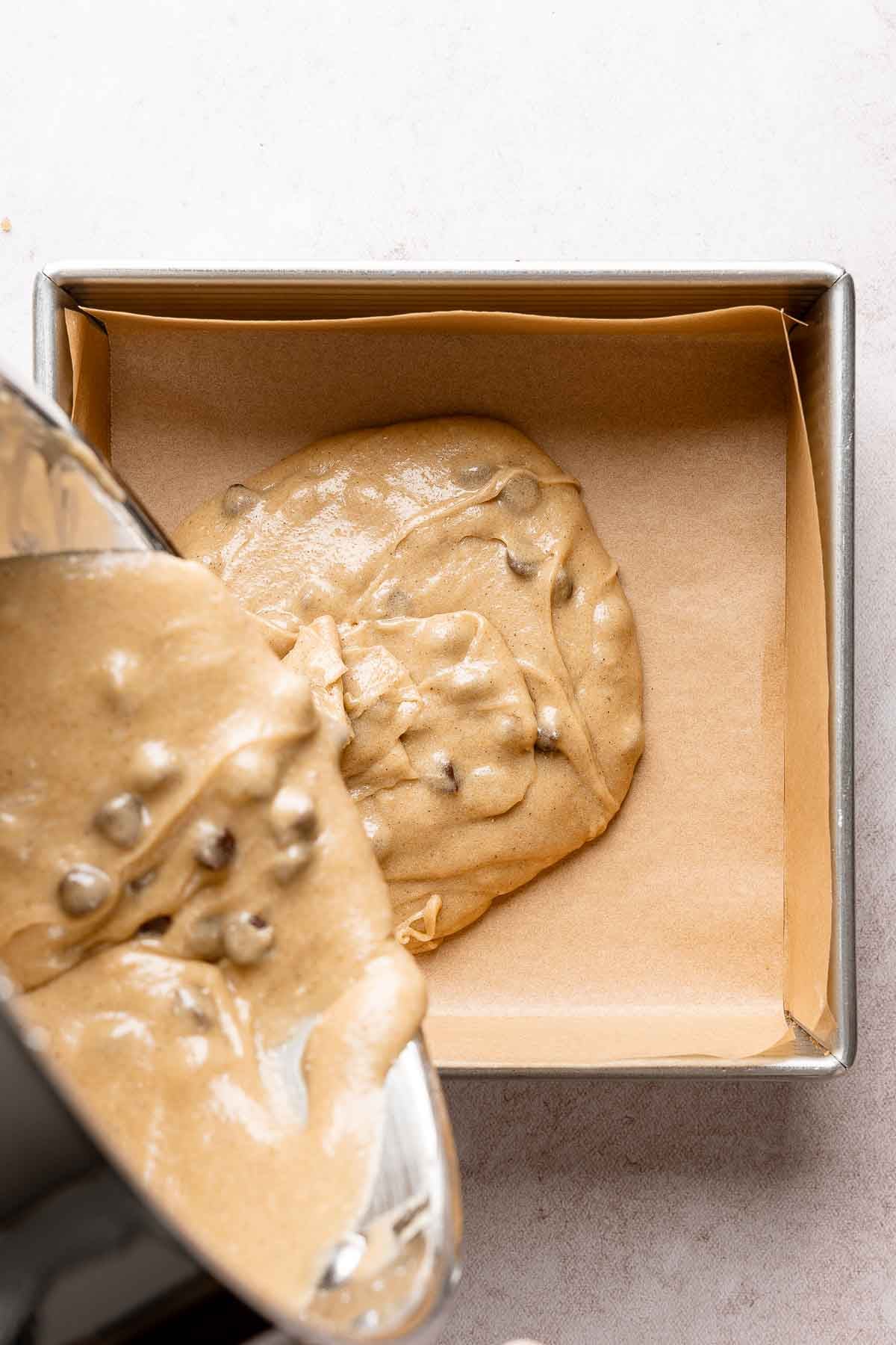 Blondie batter poured into parchment-lined square baking pan.
