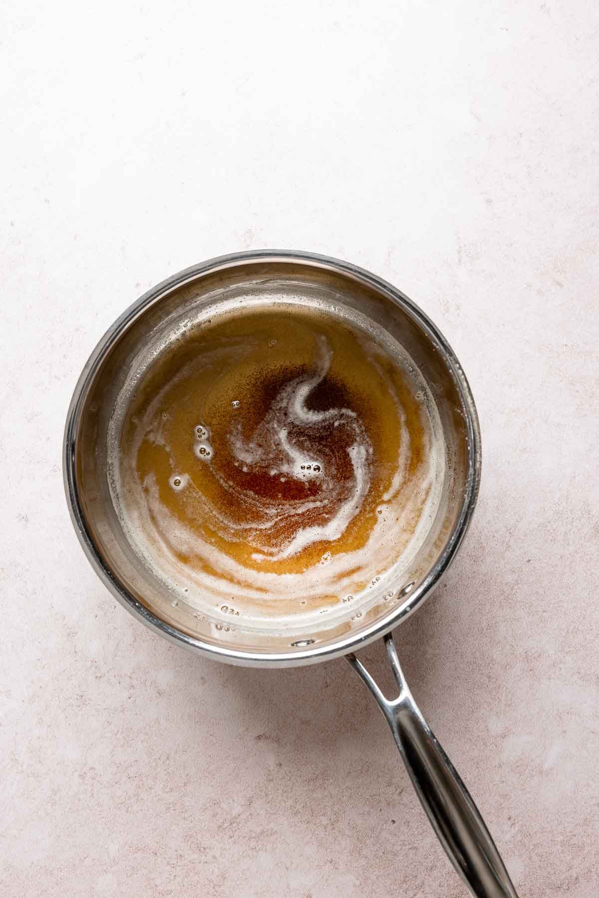 Brown butter in saucepan with bubbles on top.