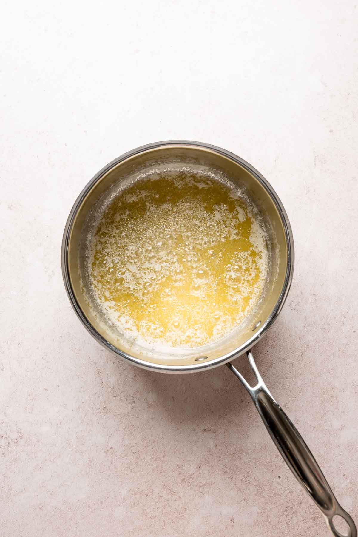Butter simmering in a saucepan with small bubbles forming as the water cooks off.
