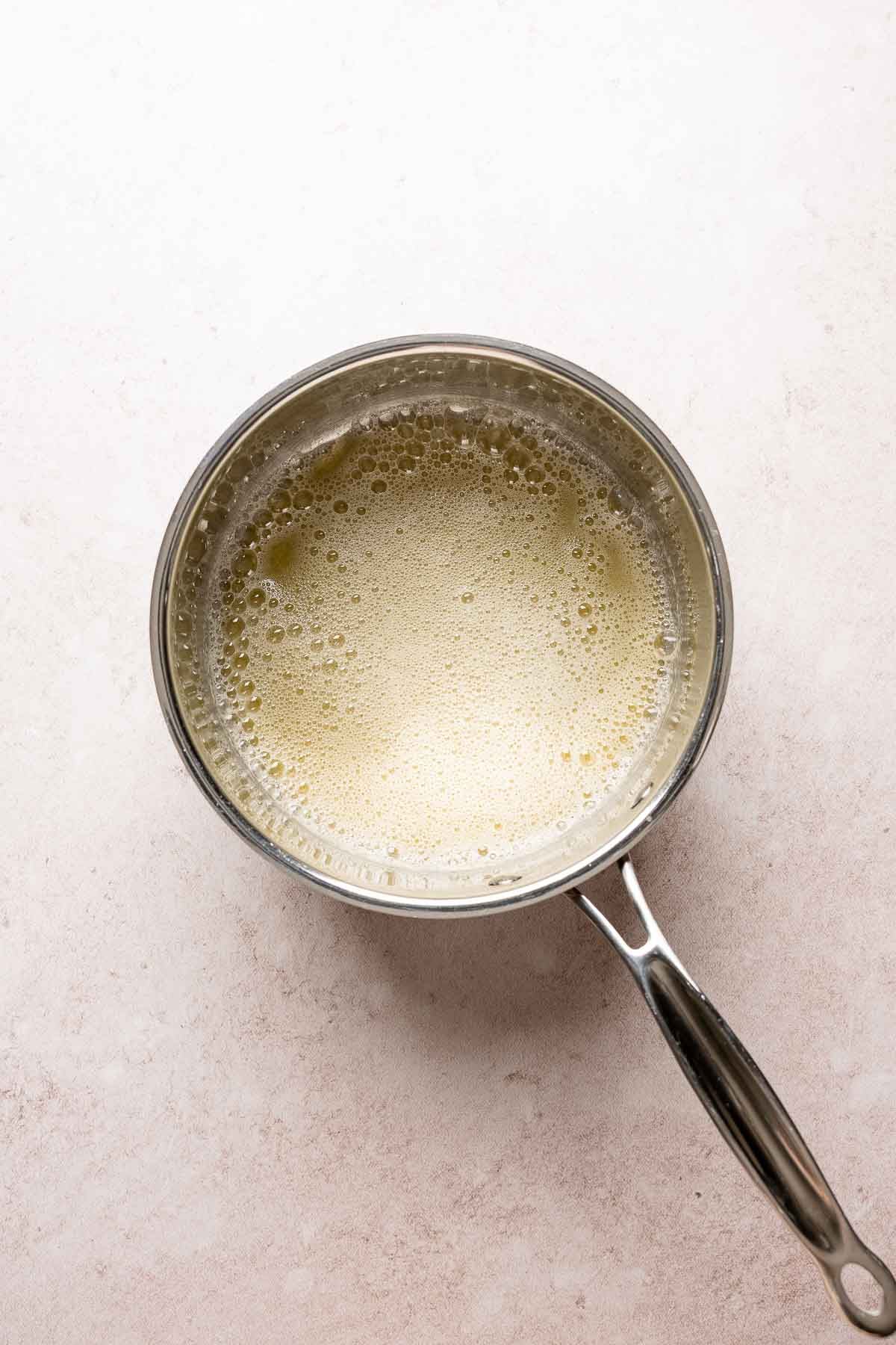 Foamy melted butter cooking in a saucepan during the early stages of browning butter.