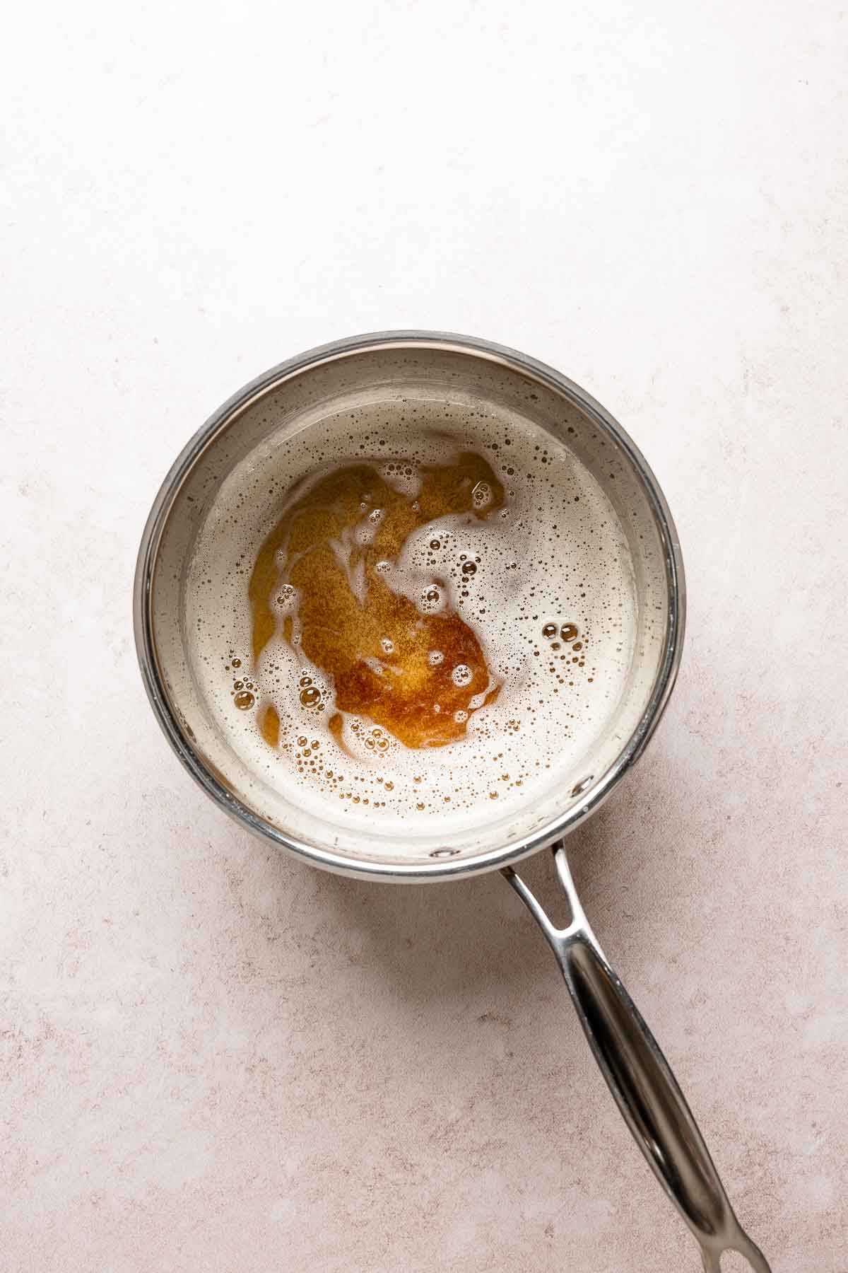 Brown butter with deep golden toasted milk solids visible beneath the foam in a saucepan.