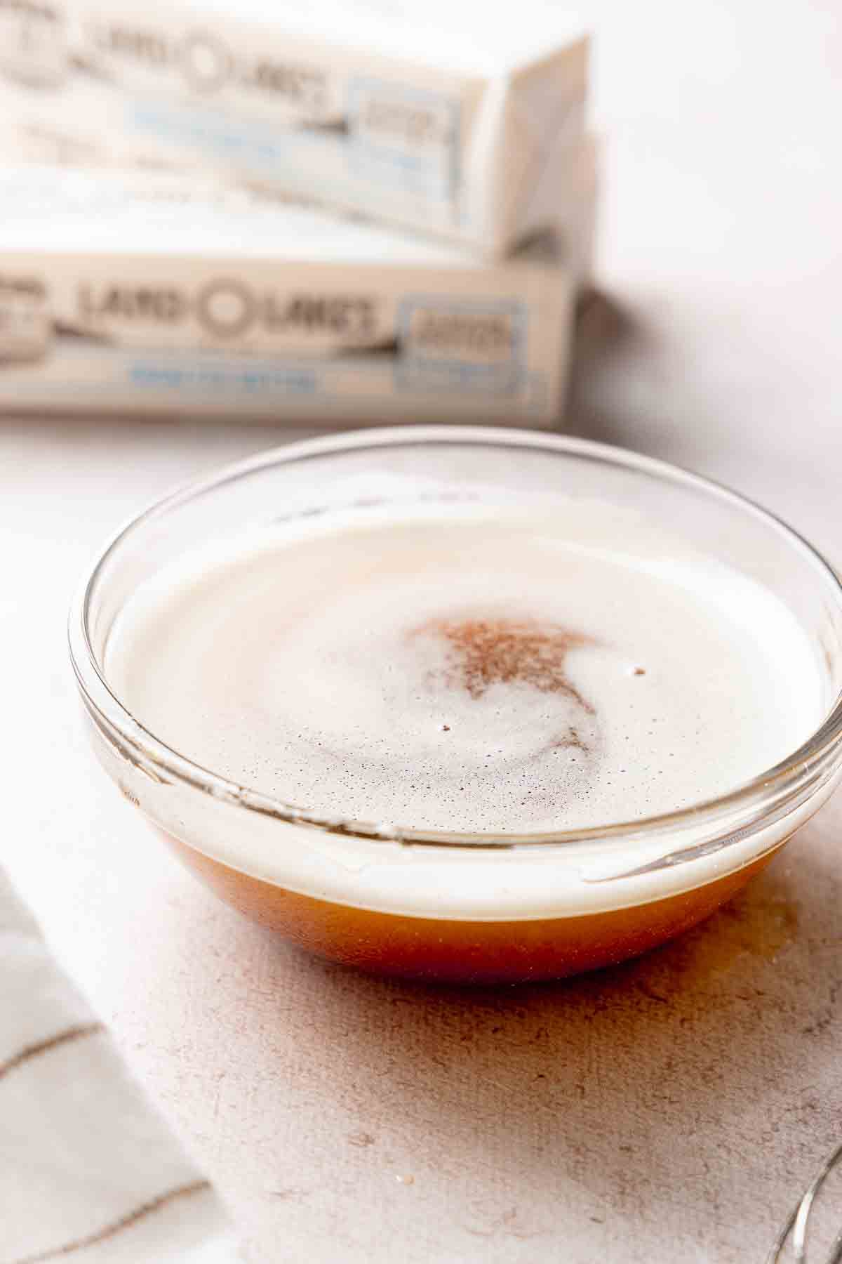Freshly browned butter in a glass bowl with golden brown milk solids and foam on top.