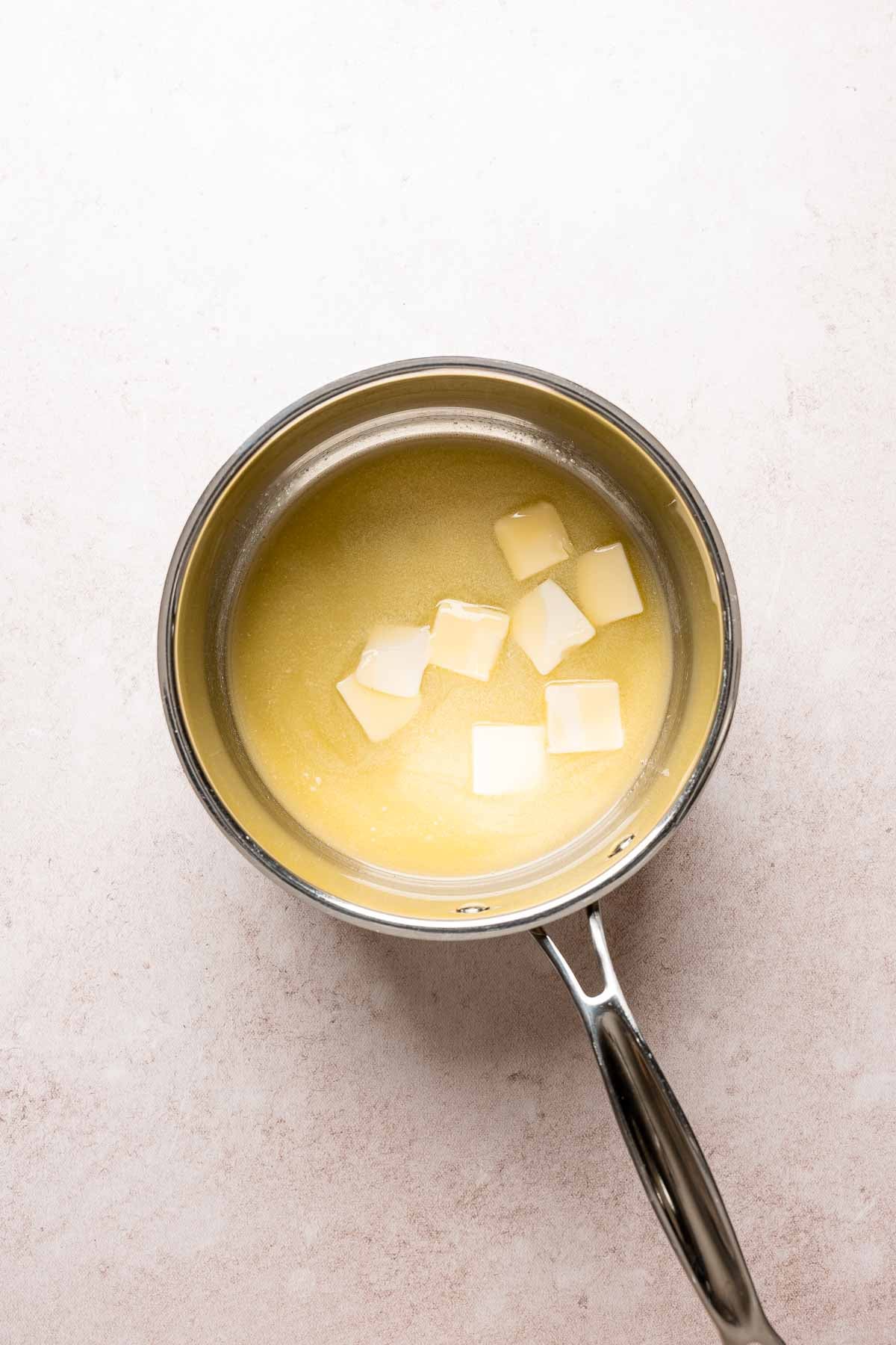 Melted butter beginning to separate in a saucepan as the milk solids rise to the surface.