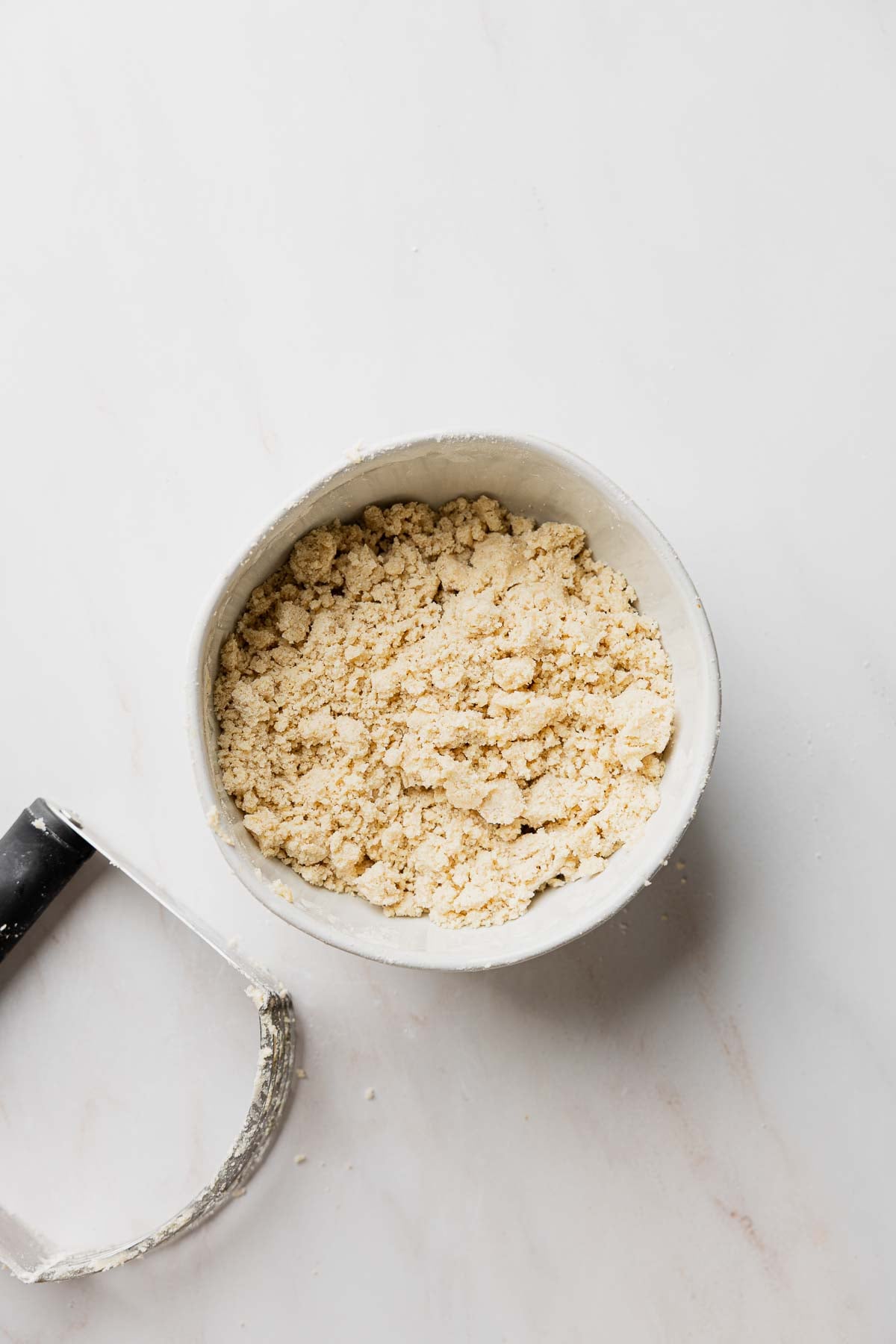 Streusel topping in small bowl next to pastry knife.