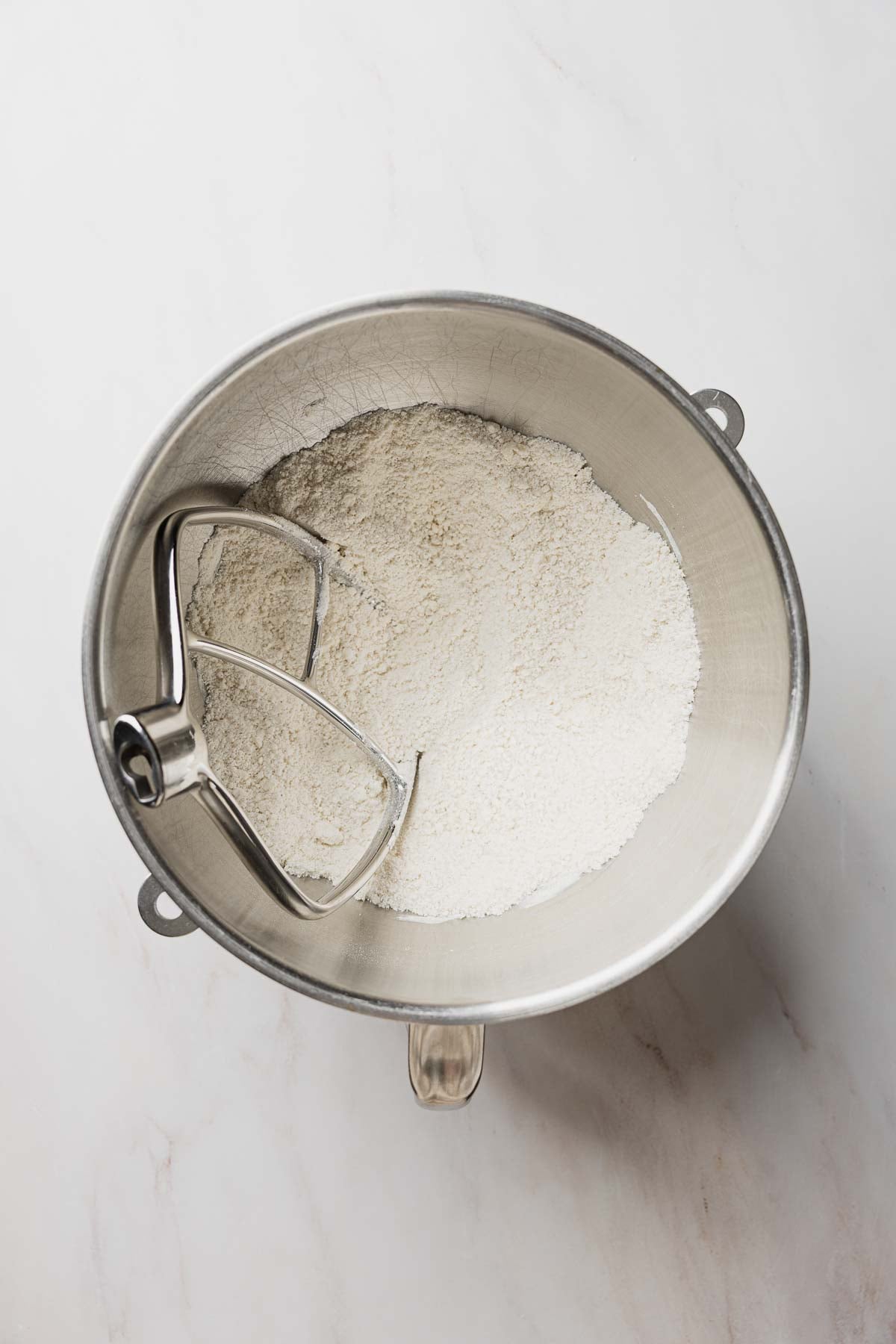Dry ingredients blended with butter in stand mixing bowl, paddle attachment resting inside bowl.