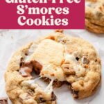 Gluten-free s'mores cookie on parchment paper, pulled apart showing gooey marshmallow and melty chocolate.
