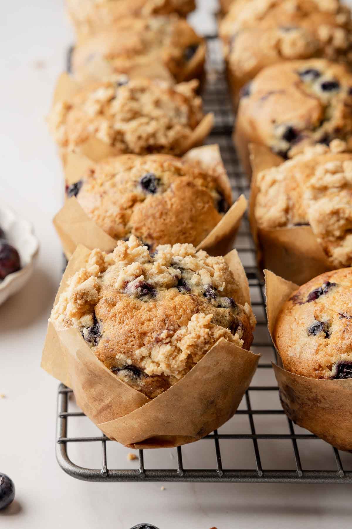 Blueberry muffins on wire rack, in homemade parchment muffin liners.