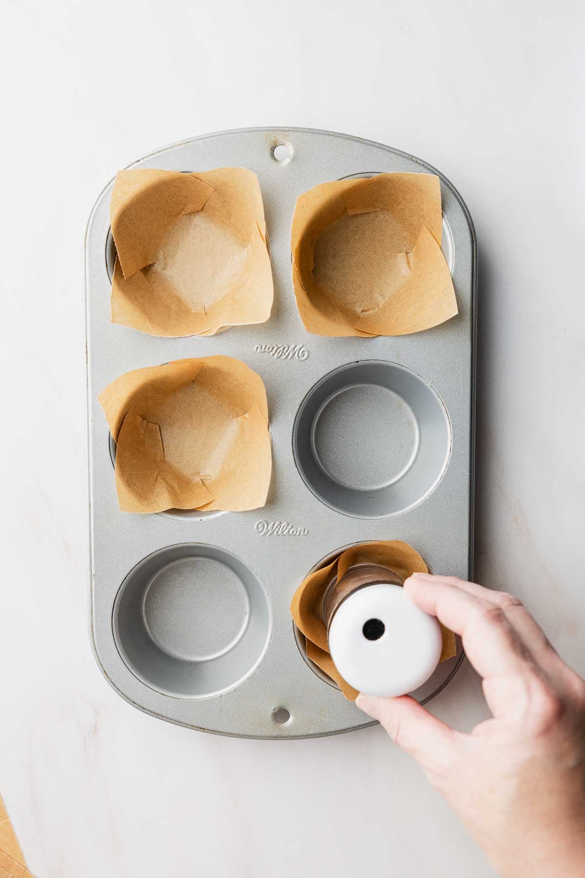 Pressing each square into the well of a muffin tin.