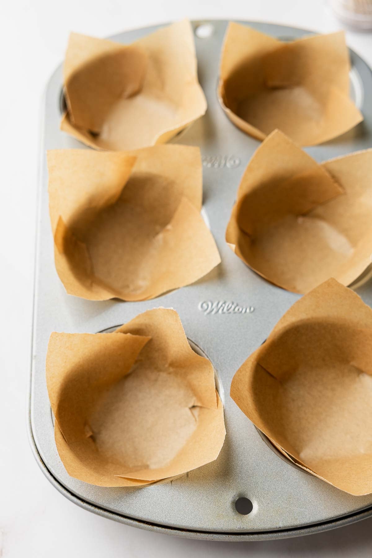 Homemade parchment paper muffin liners in muffin tin.