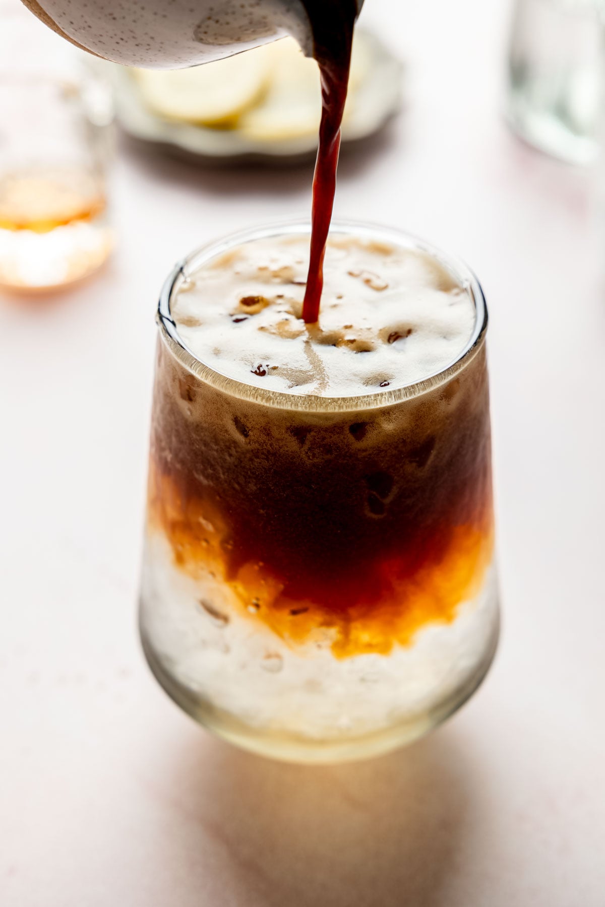 Fresh espresso being poured over sparkling water and ice to make a sparkling Americano.