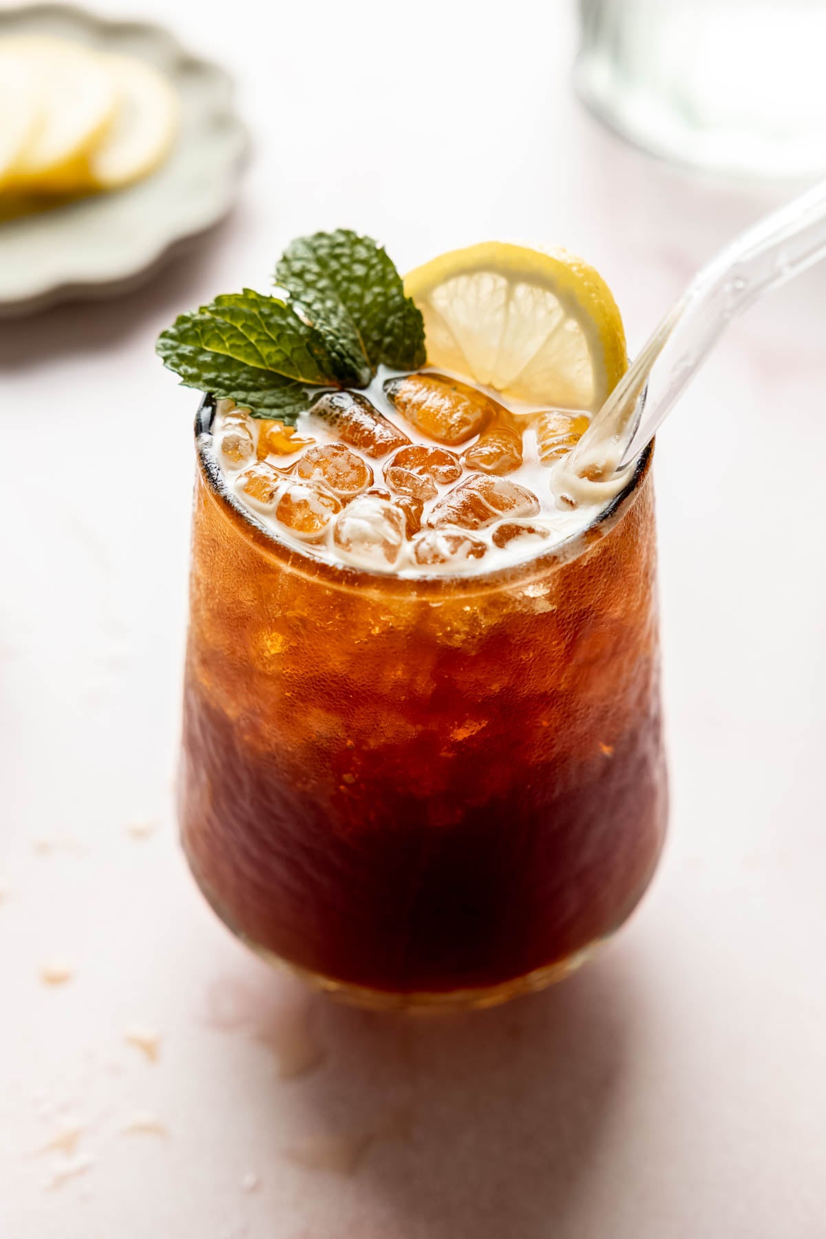A sparkling Americano in a glass with ice, garnished with fresh mint and a lemon slice.