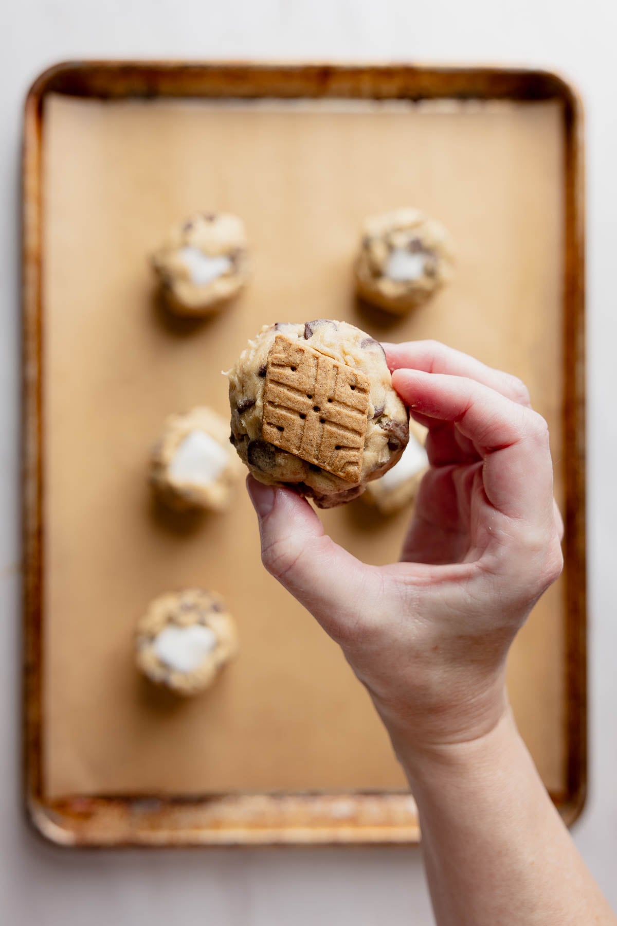 Graham cracker placed on underside of cookie dough ball.