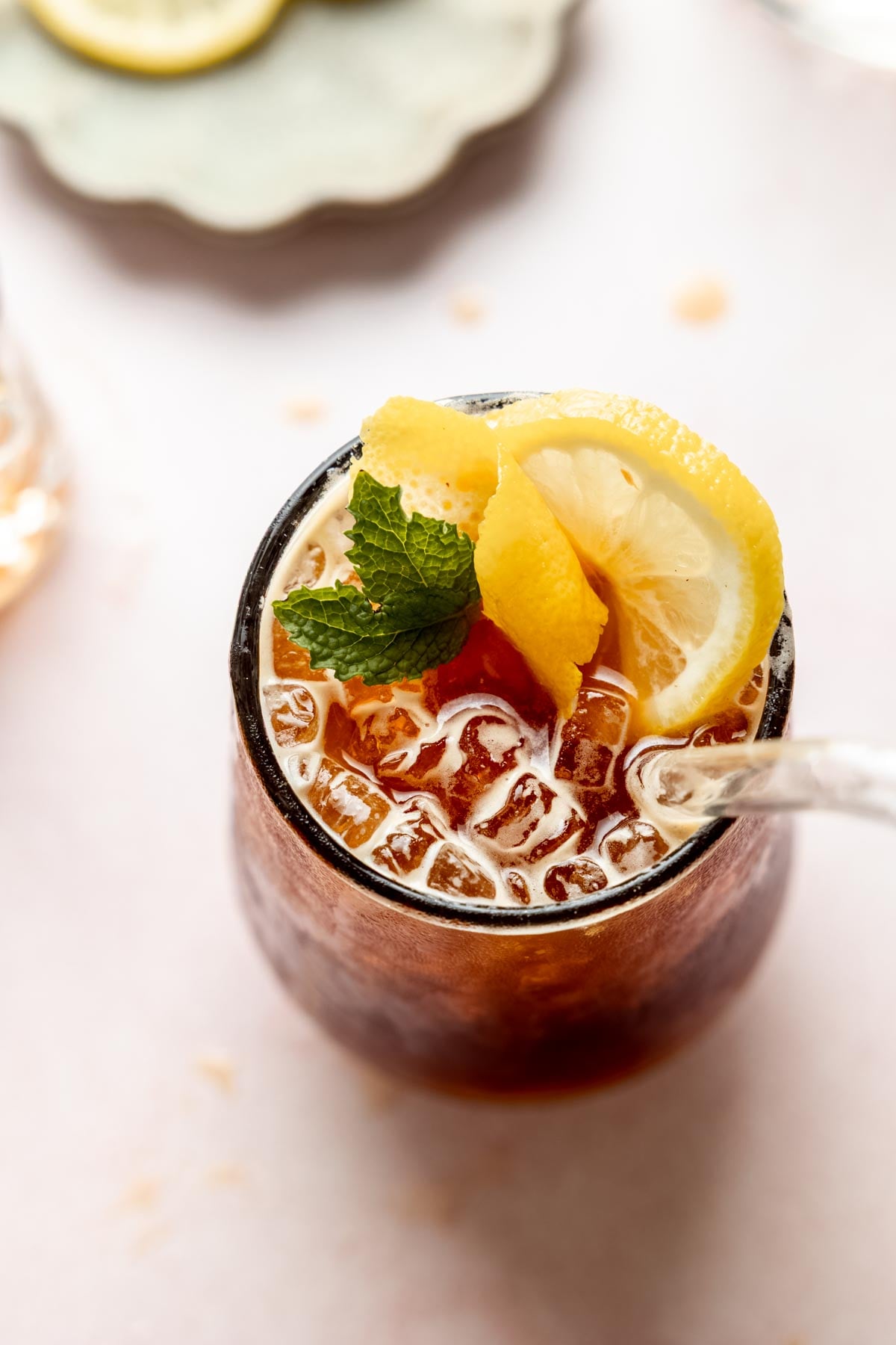 Overhead view of a sparkling Americano in a glass with ice, garnished with fresh mint and a lemon slice.