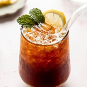 A sparkling Americano in a glass with ice, garnished with fresh mint and a lemon slice.