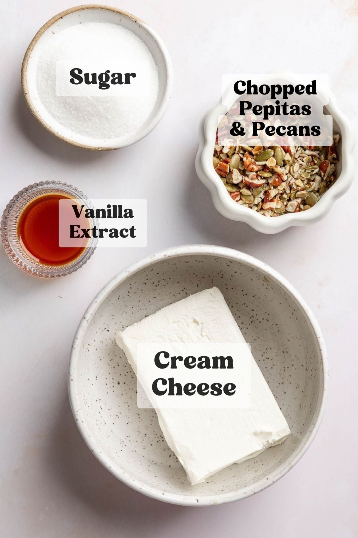 Cream cheese, granulated sugar, vanilla extract, chopped pecans and pepitas measured out in bowls.