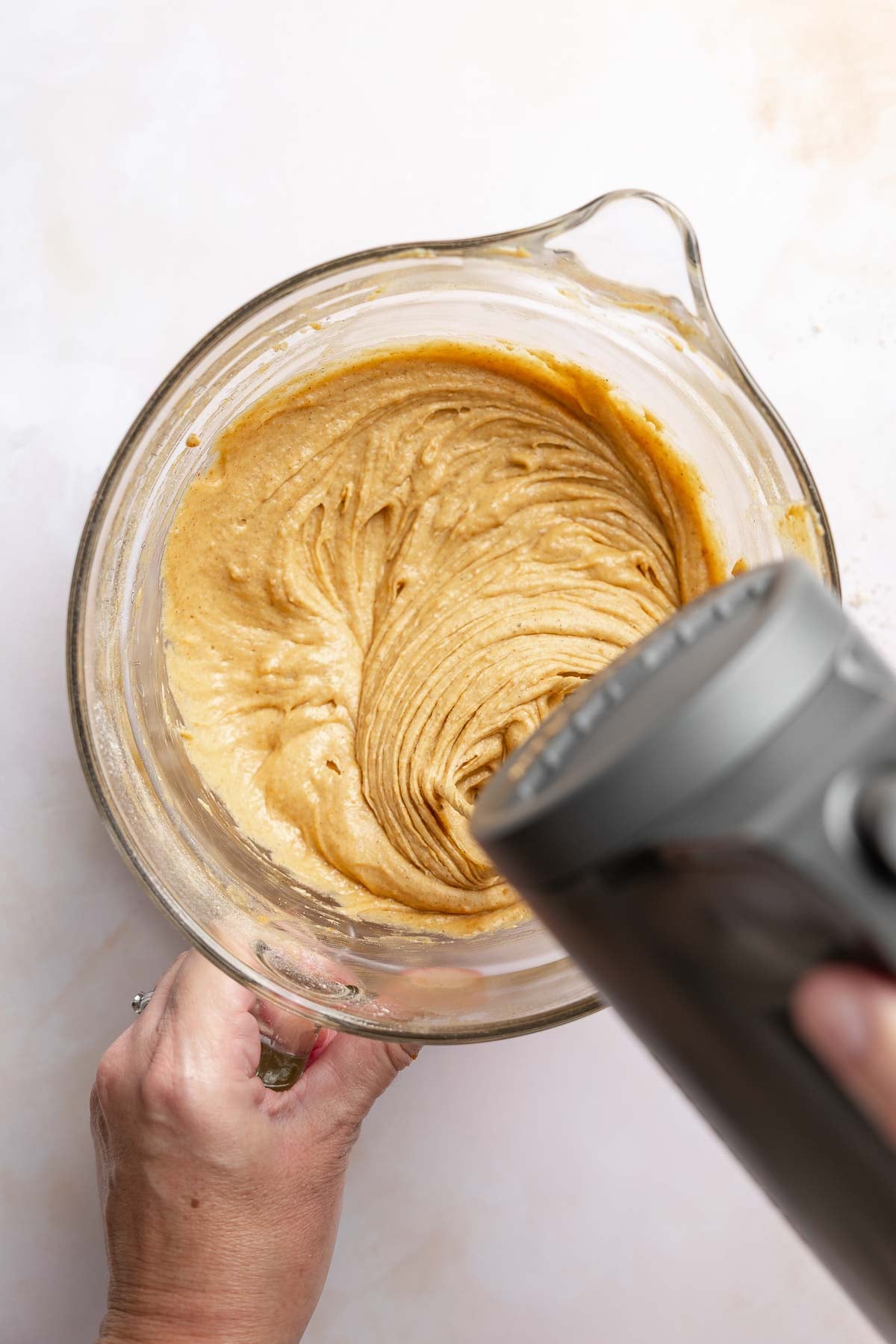 Muffin batter mixed in bowl with hand mixer.