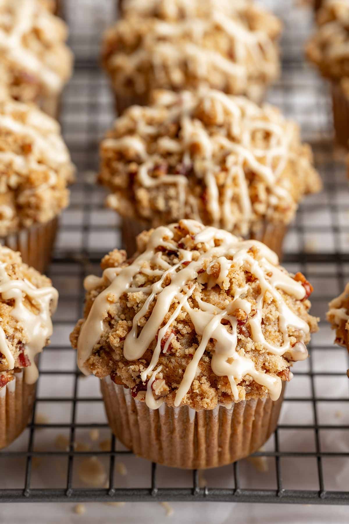 Gluten free pumpkin muffins topped with streusel and maple glaze lined up on wire rack.