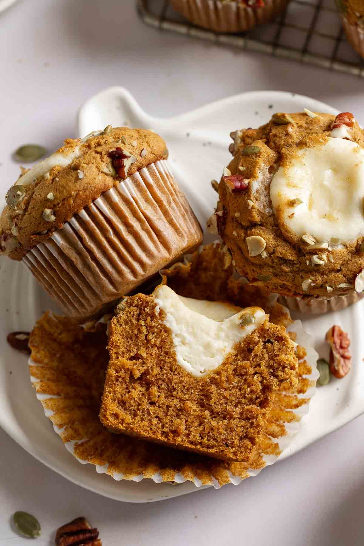 Gluten-free Starbucks cream cheese muffins on small pumpkin shaped plate, one sliced open to show filling inside.