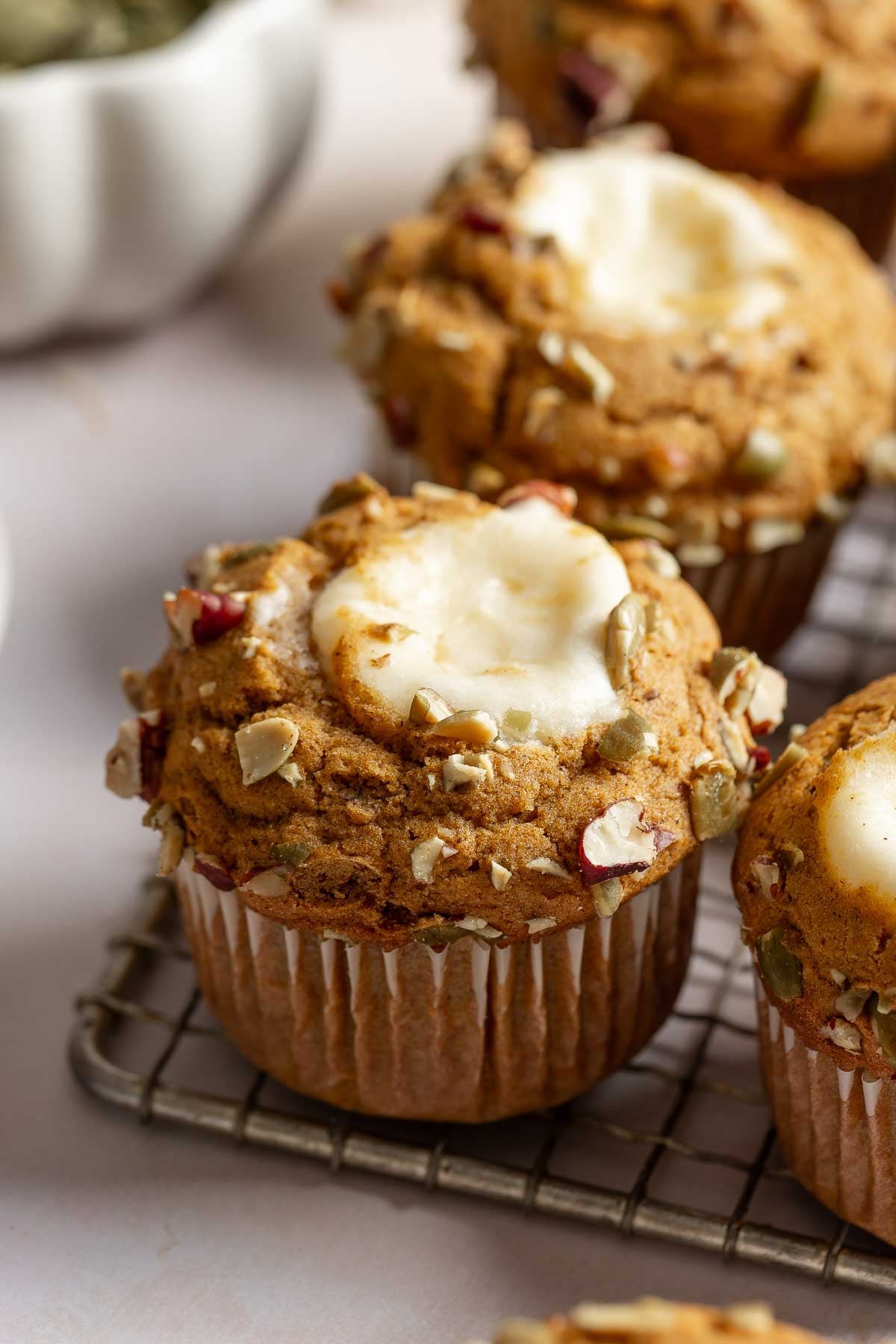 A batch of gluten-free Starbucks Pumpkin Cream Cheese Muffins on a small wire rack.