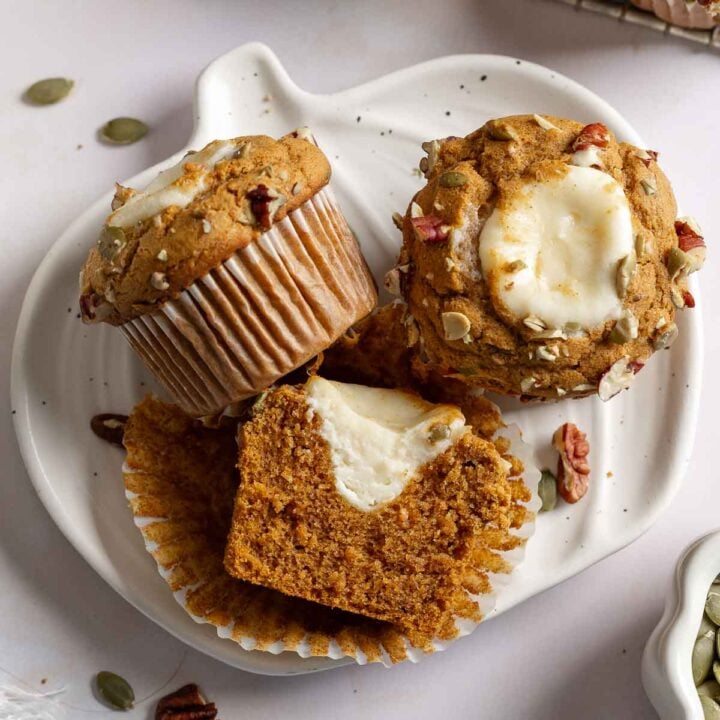 Gluten-free Starbucks cream cheese muffins on small pumpkin shaped plate, one sliced open to show filling inside.