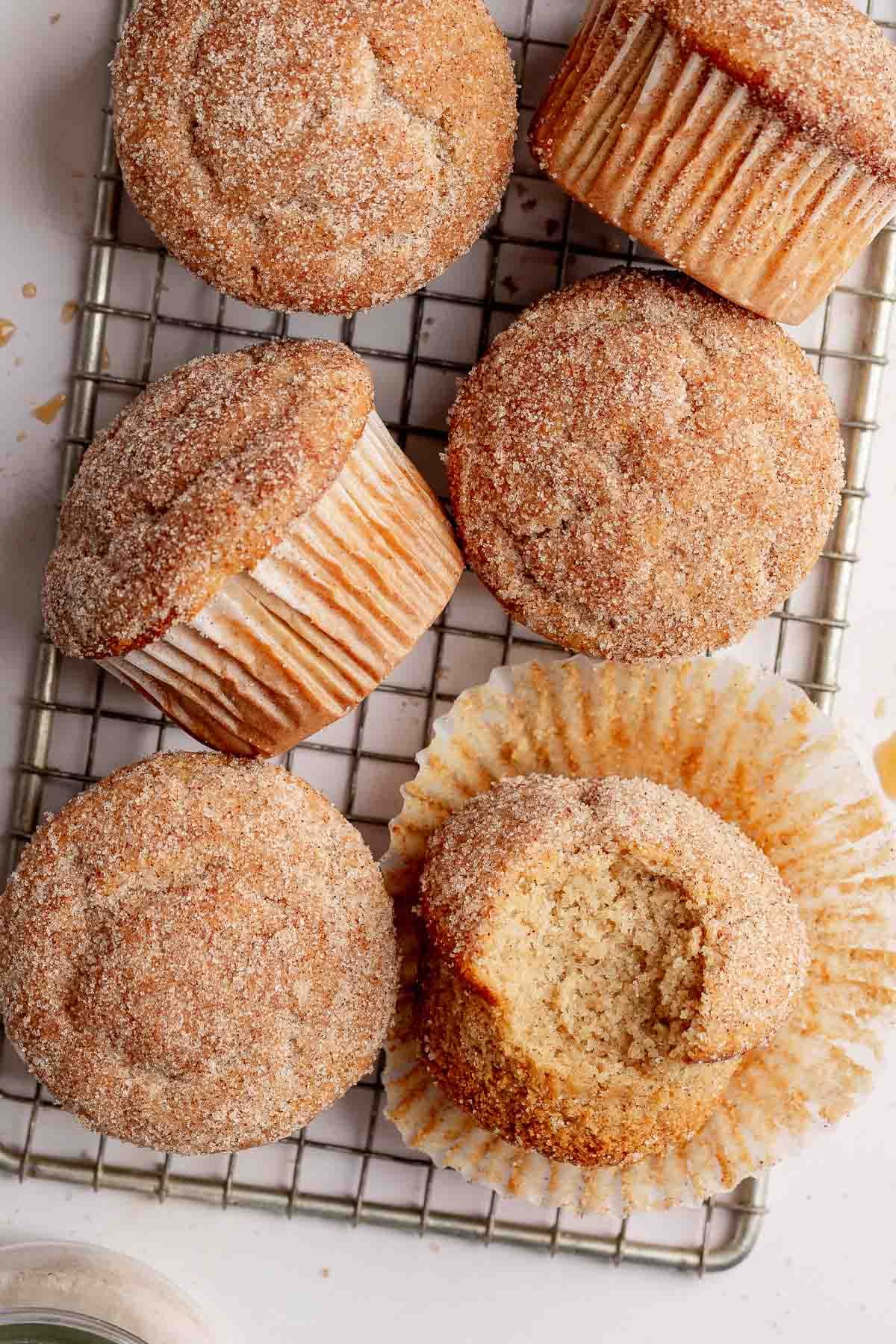 Gluten-free apple cider donut muffins on small rack, one with bite taken.