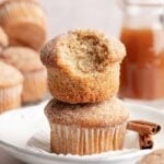 Stack of two apple cider donut muffins, one with bite taken.