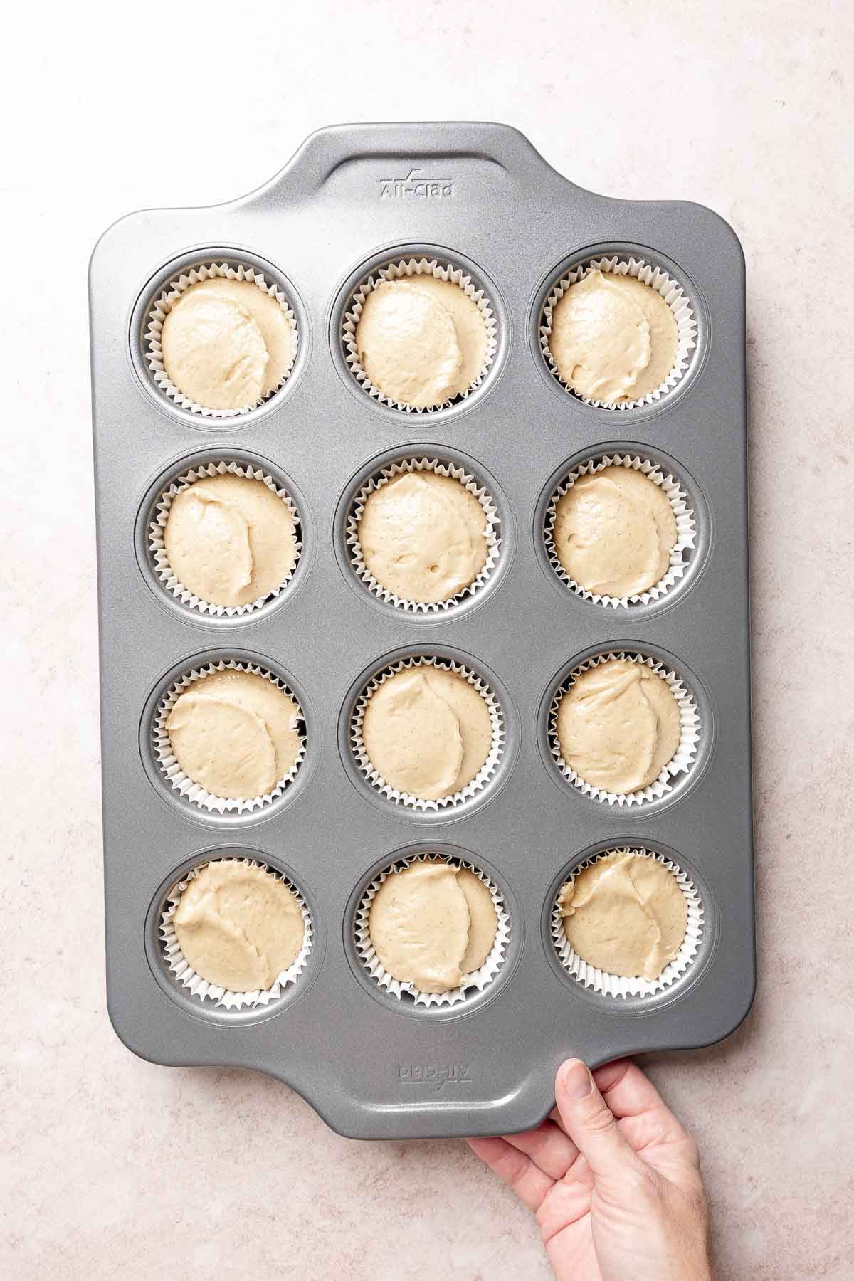 Muffin batter divided equally amongst 12 muffin cups.