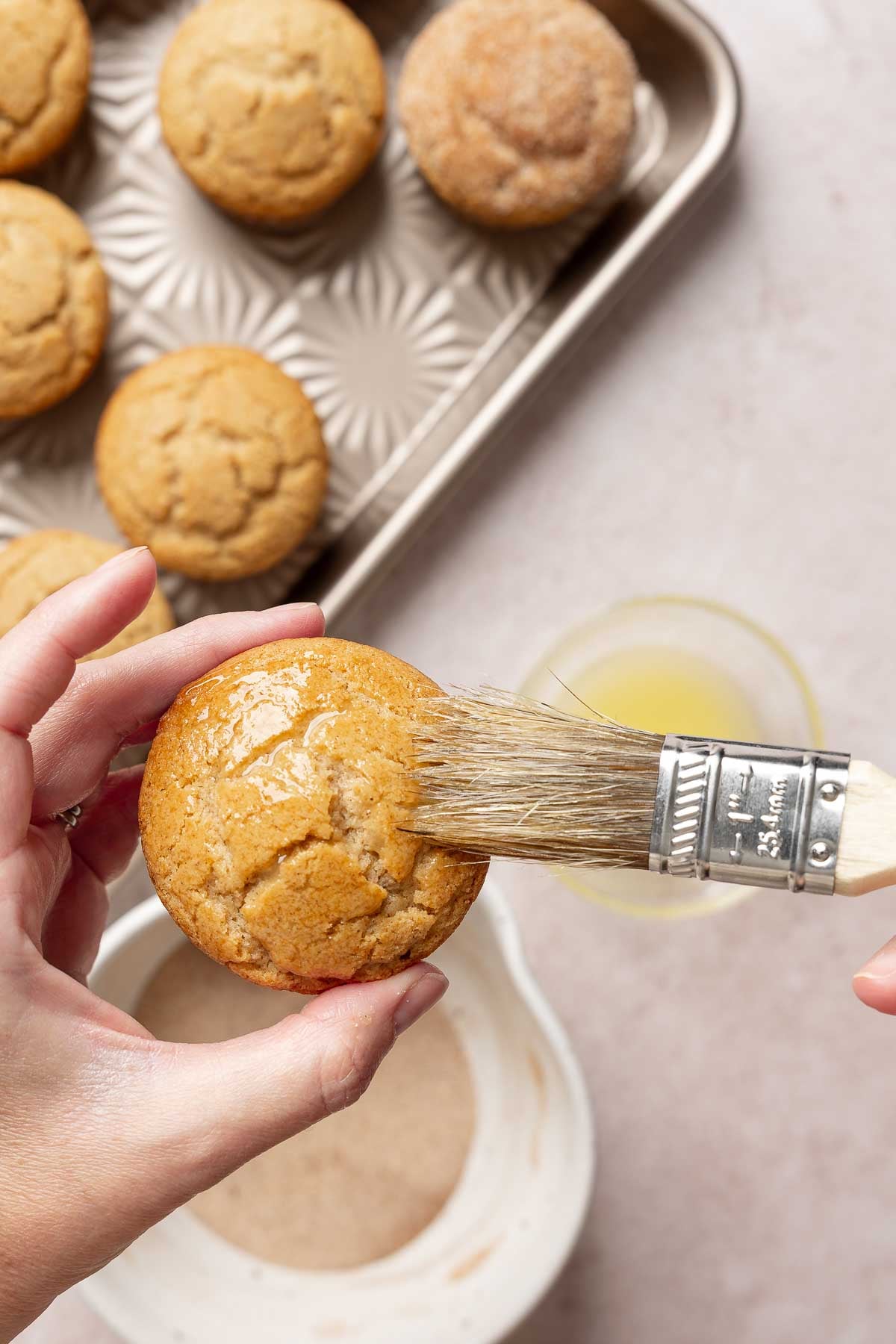 Brushing top of muffin with melted butter.